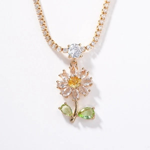 Collier feuille d'érable doré avec cristaux colorés sur un fond blanc épuré
