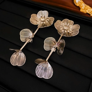 Vue macro de boucles d'oreilles fleuries dorées avec artisanat complexe en fil de métal