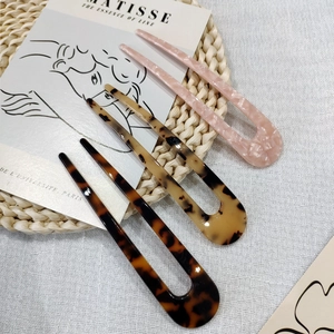Close-up of three acetate U-shaped hair pins in pink and tortoiseshell patterns