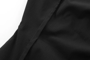 Detailed macro shot of black woven fabric texture and precise stitching on the dress