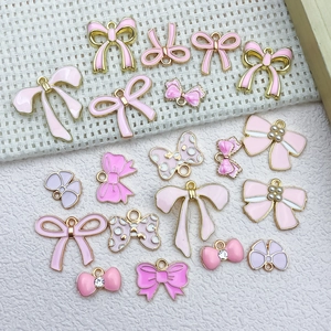 Detailed view of pink oil-dripped bow pendants with faux pearls for DIY jewelry making