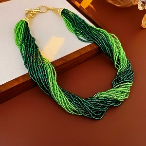 Detail of multi-strand beaded necklace in green tones with gold-tone metal clasp