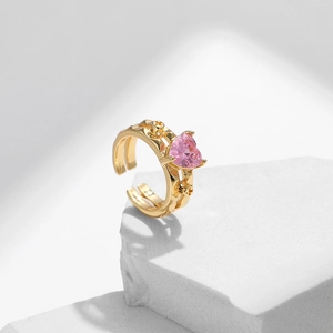 Gold plated open ring with pink heart shaped zircon stone on a white stone pedestal