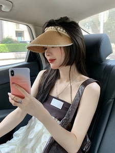 Close-up of khaki straw sun visor hat featuring elegant pearl embellishments on the brim