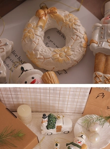 Detail view of cream ceramic Christmas ornaments with wreath and nutcracker motifs