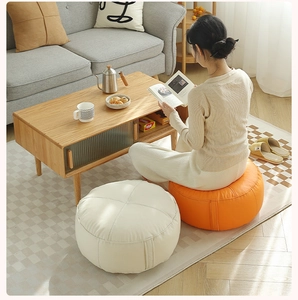 Detail of round orange and white leather floor cushions in a cozy home reading setting