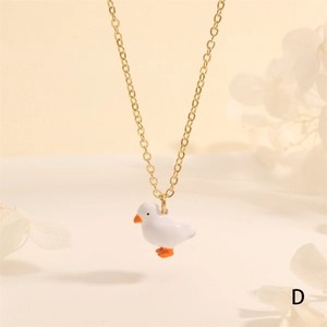 Close-up of golden necklace featuring a cute white and orange duck pendant with dried flowers