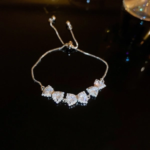 Macro shot of silver adjustable bracelet with five heart-shaped zircon stones in a bow design