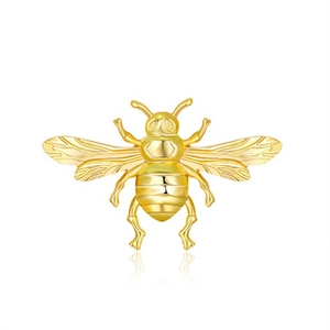 Detail view of a golden metal bee brooch with intricate textures on white background