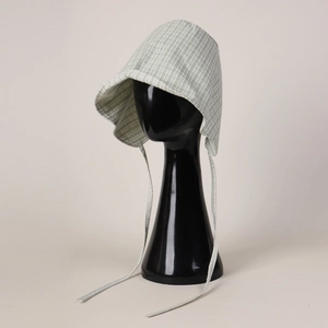 Close-up of light green checkered baby bonnet with ruffle brim and adjustable chin straps