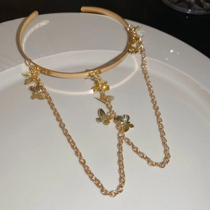 Detailed macro shot of golden metal butterfly tassels on an open bangle accessory