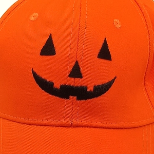 Detailed view of Halloween orange baseball cap featuring black Jack-o'-lantern embroidery