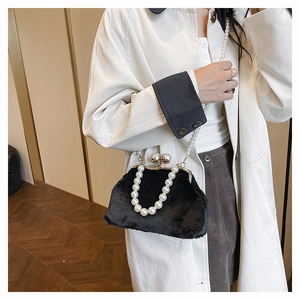 Detail of black faux fur shell bag featuring elegant pearl handle and gold metal frame