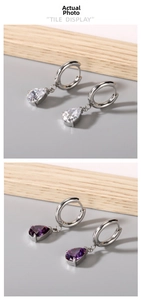 Detail of pear-cut zircon pendants in purple and clear white on silver metal hoop earrings
