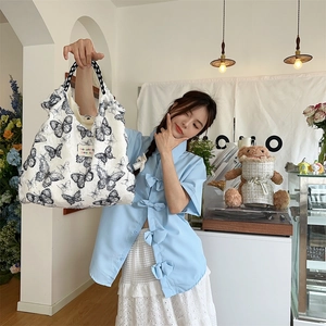Close-up of plush white tote bag with butterfly prints and checkered handle