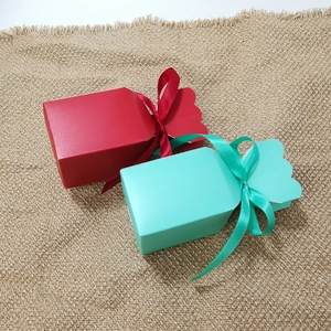 Detail of candy-shaped gift boxes in red and teal with ribbon bows on burlap texture