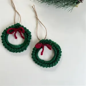Macro view of handmade crochet Christmas wreath with red bow and rustic twine loop