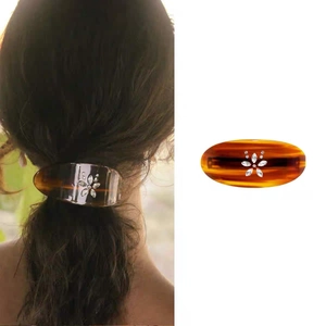 Detail of amber acetate hair clip with rhinestone flower patterns and model view