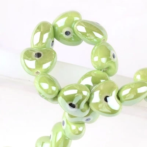 Macro shot of green heart-shaped ceramic evil eye beads for handmade jewelry making
