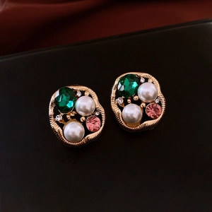 Macro shot of vintage gold earrings with green gemstones and elegant pearls