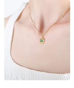 Detail of vintage gold pendant necklace with square green gemstone and radiant textures