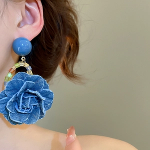 Gros plan de boucles d'oreilles roses en denim bleu élégantes avec perles colorées