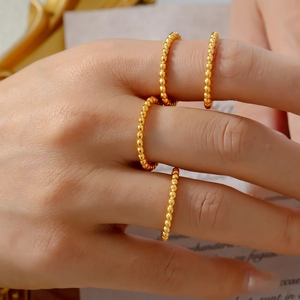 Set of four minimalist gold bead rings for women shown in a layered styling look