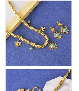 Detailed shot of golden turquoise clover necklace and matching earrings on blue background