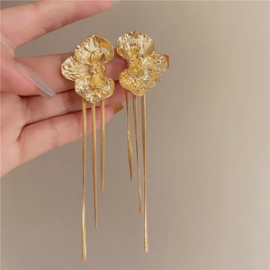 Gros plan sur des boucles d'oreilles fleurs dorées avec de fines chaînes en pompon