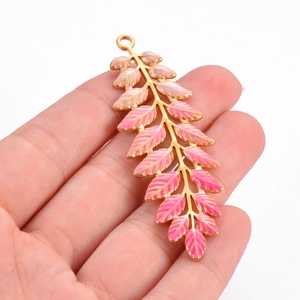 Pink and gold stainless steel leaf pendant accessory held by hand for scale