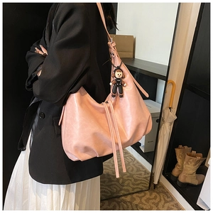 Pink PU leather tote bag shown on shoulder with natural drape and soft pendant detail