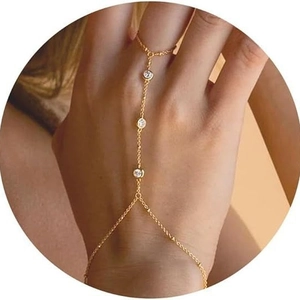Close-up of gold chain finger bracelet with three circular sparkling zircon stones