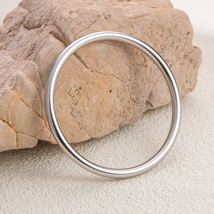 Detailed view of a polished silver minimalist bangle resting on a natural stone background
