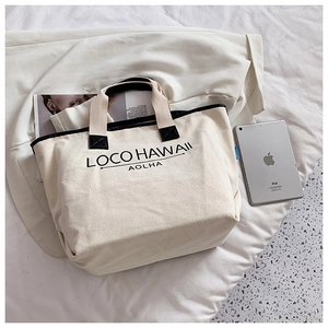 Flachbild-Detail einer cremefarbenen Canvas-Tasche mit schwarzem Buchstabendruck