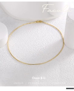 Macro shot of gold minimalist faceted snake chain necklace on white stone display