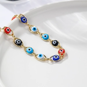 Bohemian gold chain bracelet featuring colorful evil eye beads on a white ceramic tray