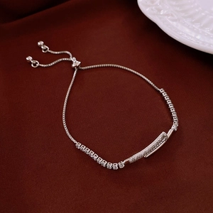 Détail du bracelet réglable en argent avec oxydes de zirconium sur fond de soie rouge