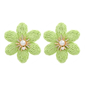 Macro detail of hand-woven green raffia flower earrings with pearls and crystals