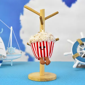 Close-up of cute popcorn plush pendant with a white bead chain hanging on wood stand