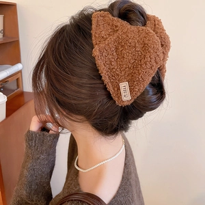 Detail van bruine teddy fleece haarklem met geweven YYDS-label op het haar
