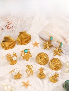 Dettaglio set gioielli con stelle marine, conchiglie e pietre azzurre su sabbia bianca