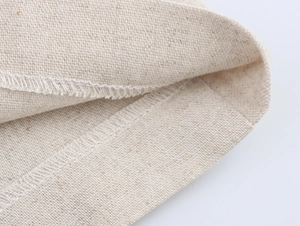 Vista macro dettagliata della trama del lino beige e della cucitura overlock professionale