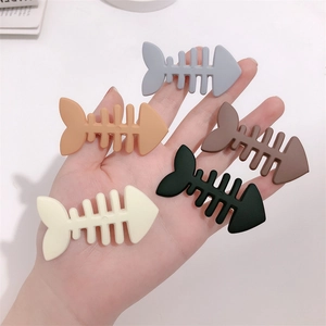 Set of five colorful fishbone hair clips in matte plastic held in hand on white background