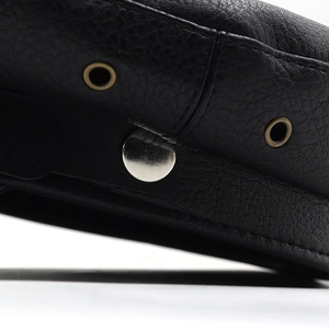 Detail of black pebbled leather texture with bronze eyelets and silver metal button