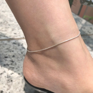 Minimalistisches silbernes Schlangen-Fußkettchen für Damen auf einer Marmoroberfläche