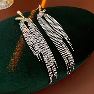 18k gold plated knot earrings with long silver tassel chains on green velvet