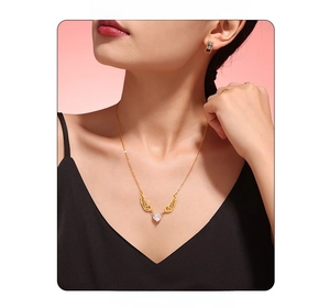 Detail of angel wing pendant with heart-shaped zircon on a gold-tone necklace