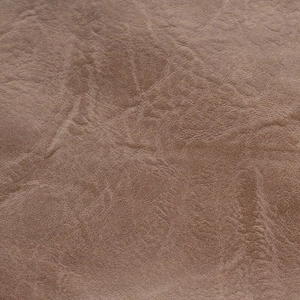 Close-up of brown PU leather with lychee texture and soft creases on a crossbody bag