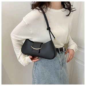 Modern black crescent shoulder bag with golden hardware shown in a lifestyle indoor setting