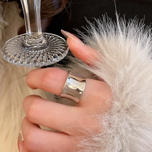 Detail of a wide concave silver metal ring with high polish finish worn on finger
